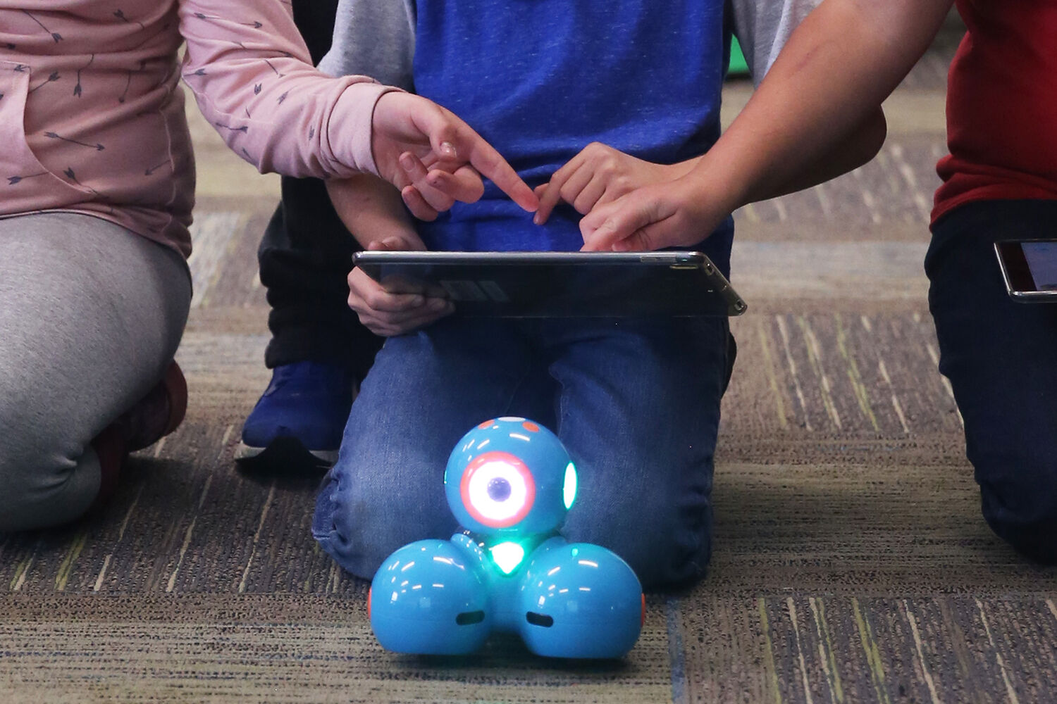 Two neighboring classmates help fix a coding issue on the iPad
